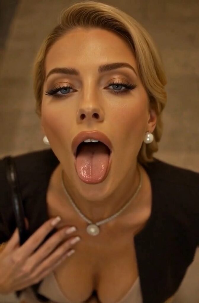 A close-up shot from above of a blonde, glamorous beauty's face, with her tongue boldly sticking out in a seductive, extremely erotic expression